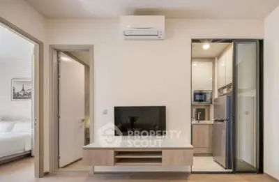 Modern apartment interior with sleek kitchen and cozy living area featuring air conditioning and wall-mounted TV.