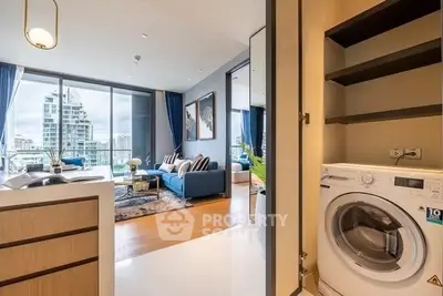 Modern apartment with open layout, featuring a cozy living room and in-unit washing machine.
