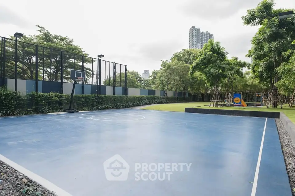 Modern outdoor basketball court with lush greenery and cityscape view.