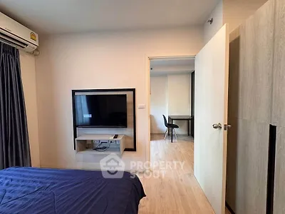 Modern bedroom with wall-mounted TV and open door to study area