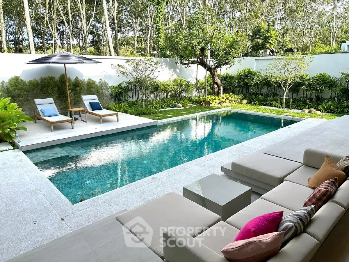 Luxurious outdoor pool area with modern seating and lush greenery, perfect for relaxation and entertainment.