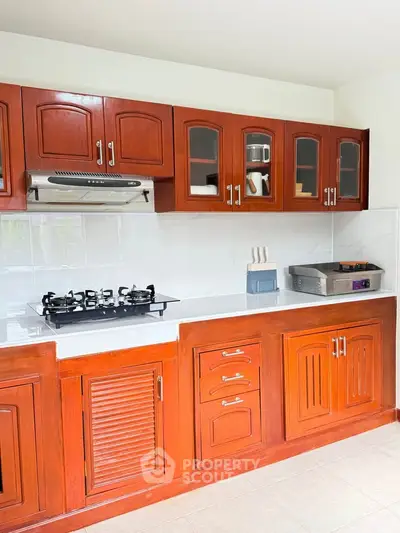 Spacious kitchen with wooden cabinets and modern gas stove