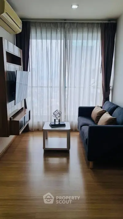 Modern living room with sleek furniture and large windows offering natural light.