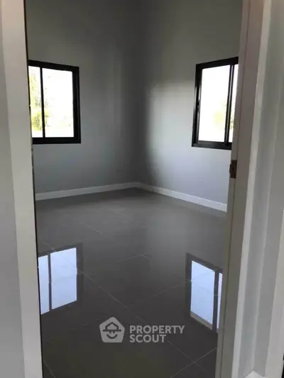 Spacious empty room with glossy tiled floors and large windows.