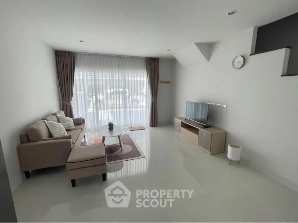 Spacious modern living room with sleek furniture and large window for natural light.