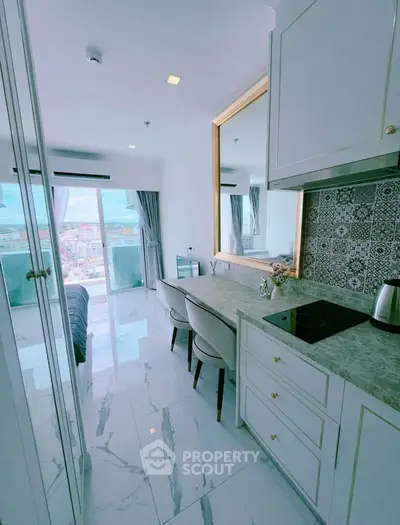 Modern kitchen with marble countertops and city view from balcony in stylish apartment.
