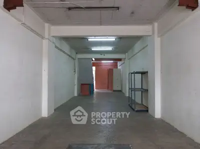 Spacious empty storage room with concrete floor and metal shelving.
