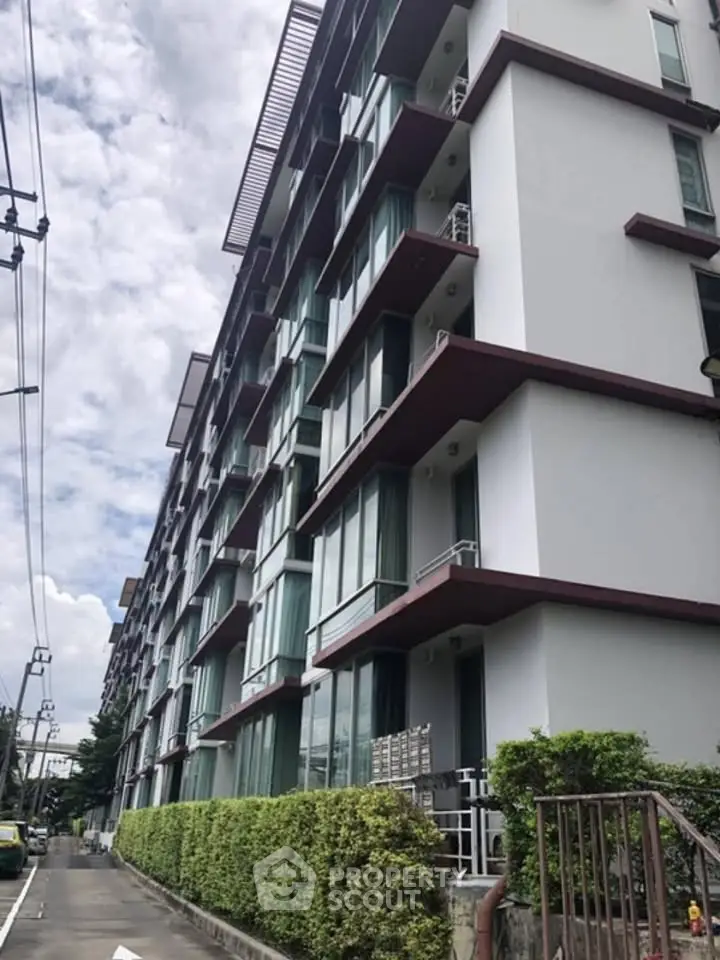 Modern apartment building exterior with large windows and lush greenery