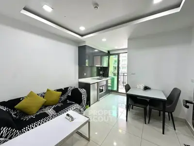 Modern living room with sleek kitchen and dining area, featuring stylish decor and ample natural light.