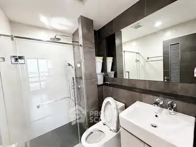 Modern bathroom with glass shower and sleek fixtures in contemporary apartment.