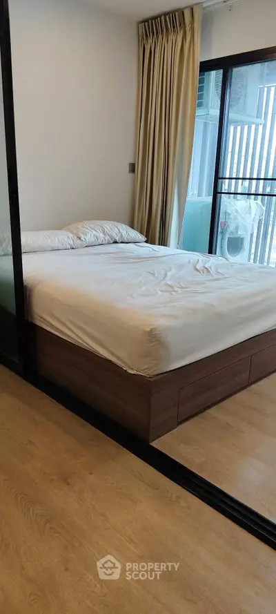 Modern bedroom with large window and wooden flooring in a stylish apartment.