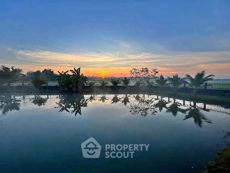Stunning sunrise view over tranquil pond with lush greenery, perfect for serene living.
