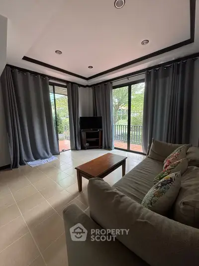 Spacious living room with large windows and cozy sofa, perfect for relaxation.