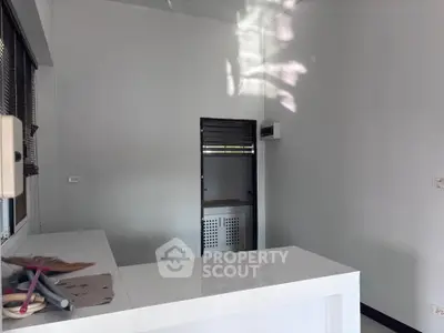 Modern minimalist kitchen with sleek white countertops and ample natural light.