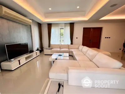 Spacious modern living room with elegant white sectional sofa and large flat-screen TV