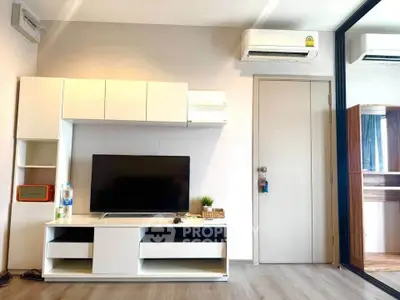 Modern living room with sleek white furniture and mounted TV, featuring air conditioning and stylish decor.