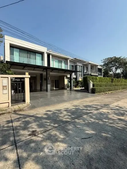 Modern two-story house with large windows and driveway in a serene neighborhood.