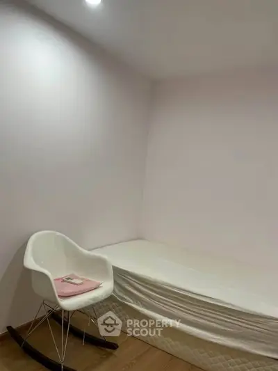 Minimalist bedroom with single bed and modern chair, perfect for cozy living.