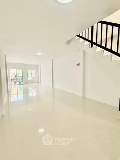 Spacious modern living room with sleek staircase and glossy tiled floors