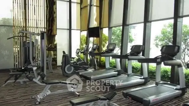 Luxurious gym with modern equipment and large windows offering a scenic view.