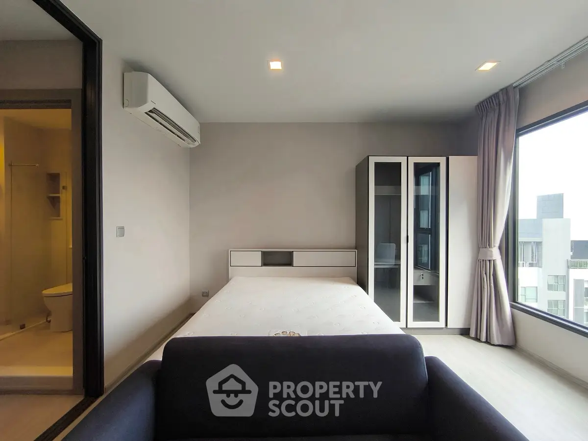 Modern bedroom with large windows and ensuite bathroom in a stylish apartment.