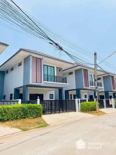 Modern two-story houses with balconies and gated driveways in a suburban neighborhood.