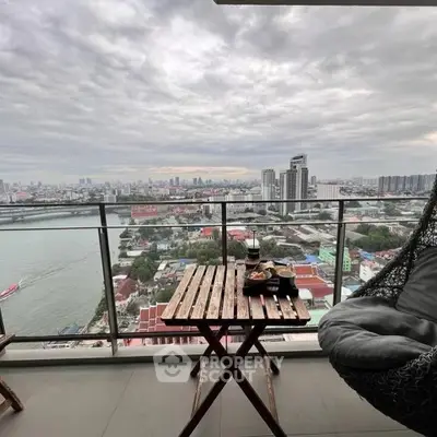 Stunning cityscape view from high-rise balcony with cozy seating and dining setup.