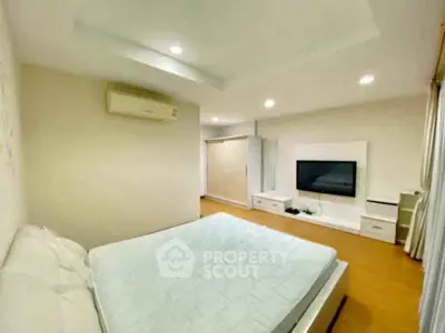 Spacious bedroom with modern decor and wall-mounted TV in a cozy apartment.