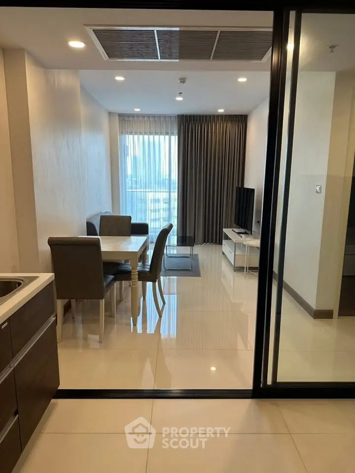 Modern living room with dining area and city view, featuring sleek furniture and large windows.