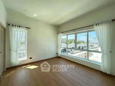 Bright empty room with large windows and wooden flooring