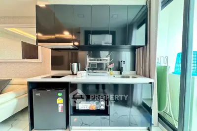Modern compact kitchen with sleek black cabinets and built-in appliances in a stylish apartment.