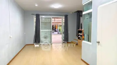 Spacious living room with wooden flooring and large windows offering natural light.