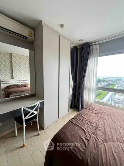 Cozy bedroom with large window offering stunning city views, featuring modern decor and ample natural light.