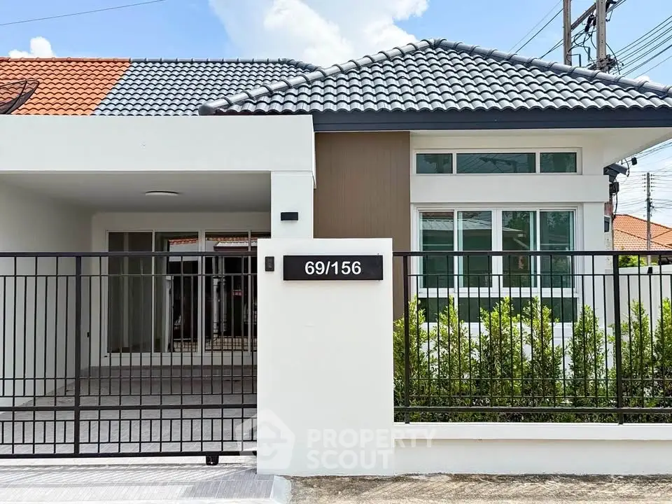 Charming single-story house with modern facade and gated entrance in a serene neighborhood.
