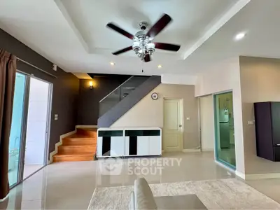 Spacious modern living room with ceiling fan and staircase