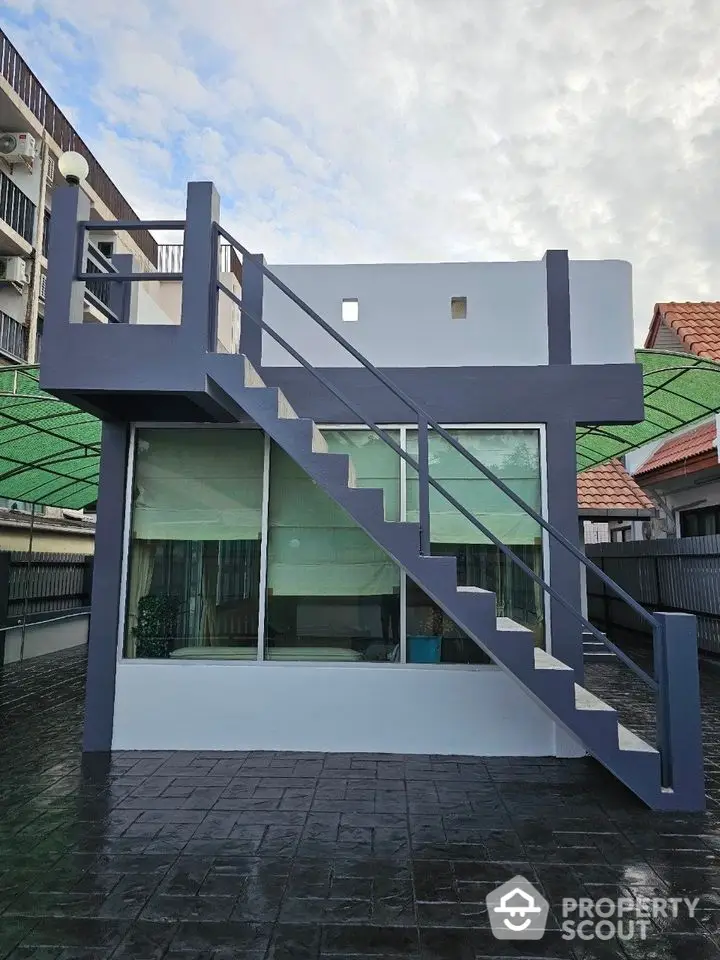 Modern rooftop terrace with sleek staircase and glass windows, perfect for urban living.