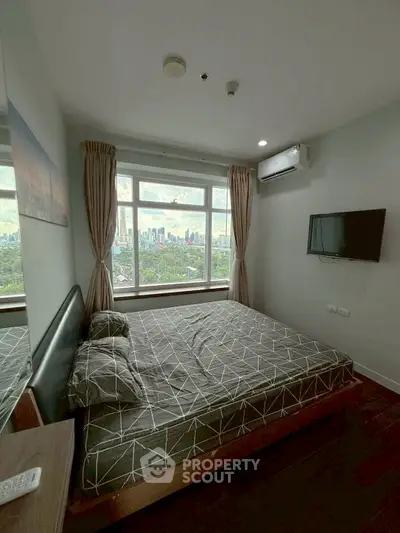Modern bedroom with city view, featuring a wall-mounted TV and air conditioning.