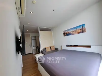 Modern bedroom with sleek design, featuring a cozy bed, wall-mounted TV, and stylish decor in a contemporary apartment.