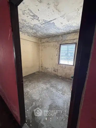 Unfinished room with peeling paint and concrete floor, potential for renovation.