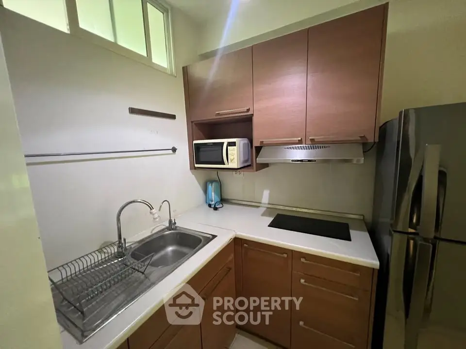 Compact kitchen with modern appliances and sleek cabinetry in a cozy apartment.