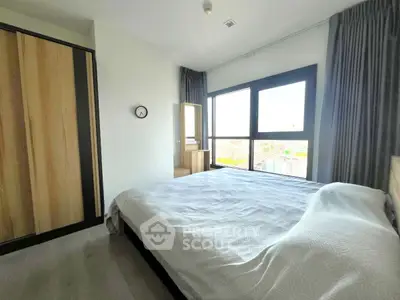Spacious bedroom with large window offering stunning city views and modern furnishings.