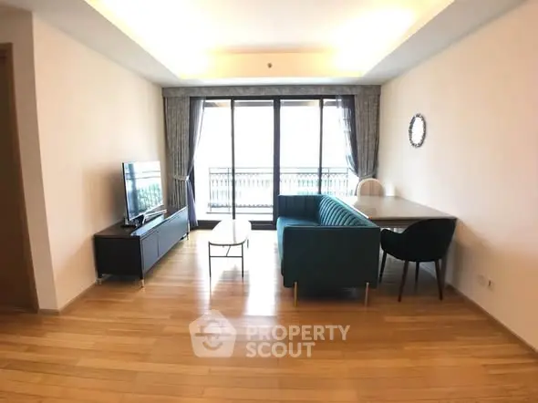 Spacious living room with modern furniture and large windows leading to a balcony.