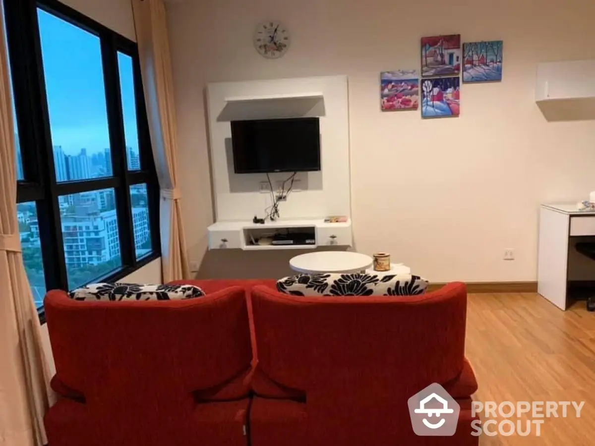 Cozy living room with red sofa and city view, perfect for relaxation.