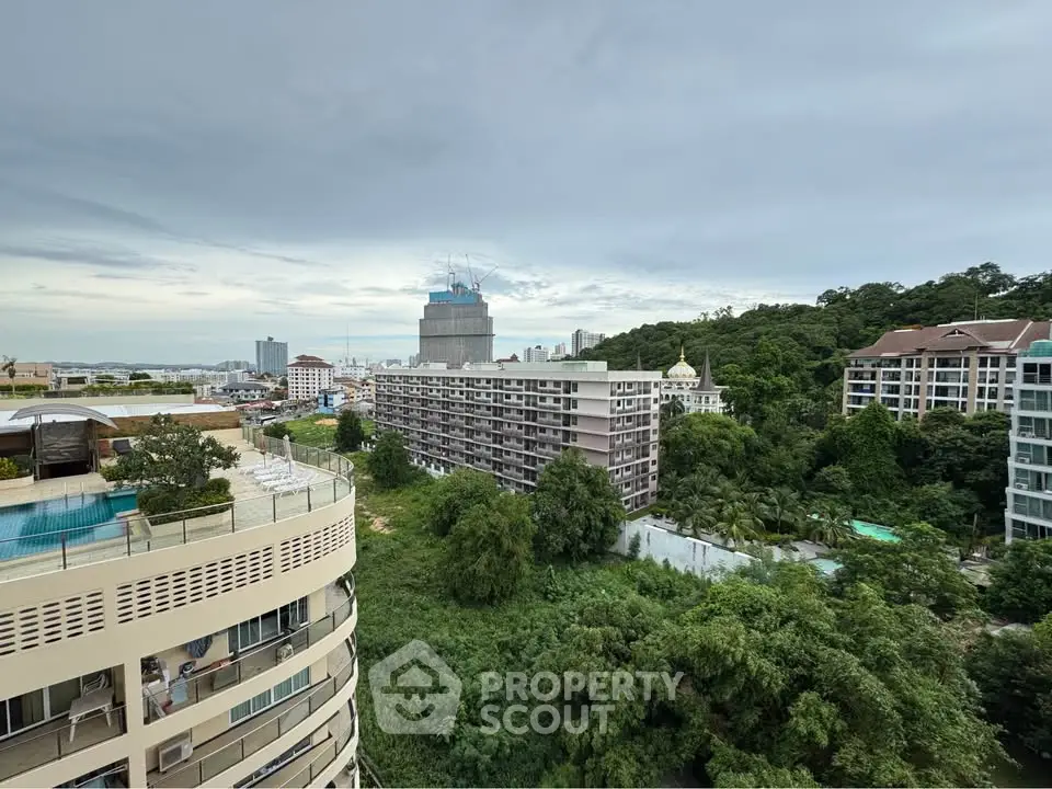 Stunning cityscape view from high-rise balcony overlooking lush greenery and urban skyline.