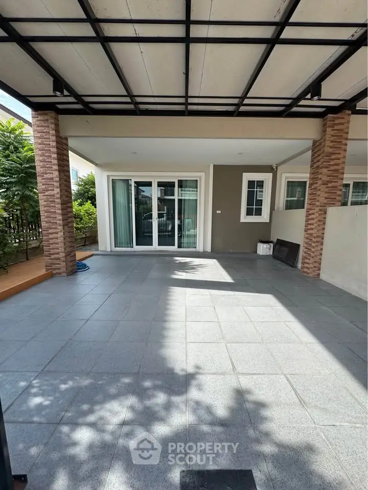 Spacious covered patio with sliding glass doors and tiled flooring, perfect for outdoor relaxation.