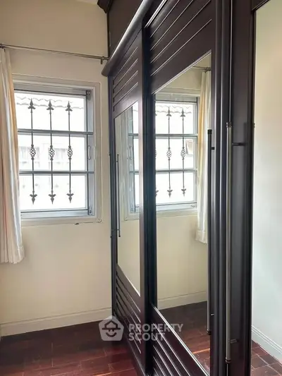 Spacious bedroom with elegant mirrored wardrobe and natural light