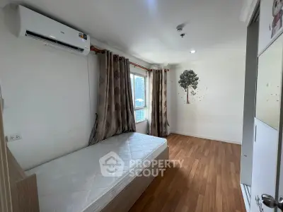 Spacious bedroom with wooden flooring and city view, featuring air conditioning and minimalist decor.