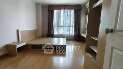 Spacious bedroom with wooden flooring and large window offering city views