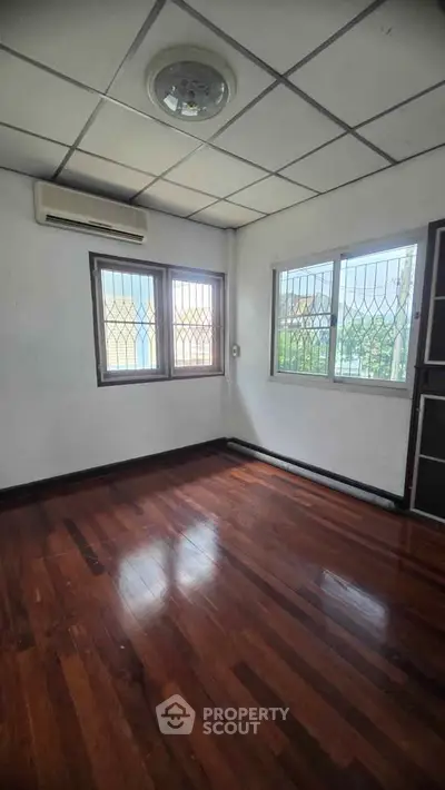 Spacious room with wooden floors and large windows, perfect for natural light.