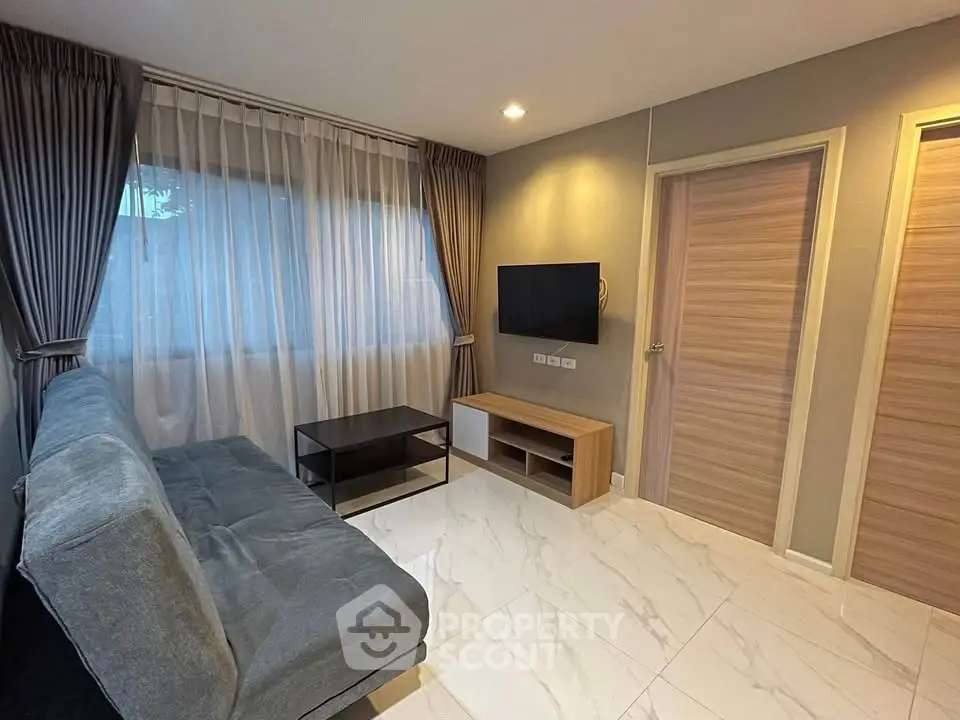 Modern living room with sleek design, featuring a comfortable sofa, wall-mounted TV, and elegant curtains.